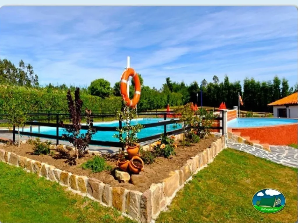 Piscina con parque infantil y vistas al entorno verde del Camping Villaviciosa, La Rasa (Asturias)
