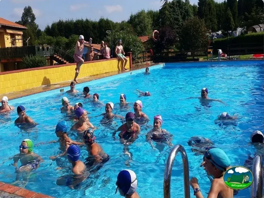 Piscina llena de bañistas con trampolín y animación del Camping Villaviciosa, La Rasa (Asturias)