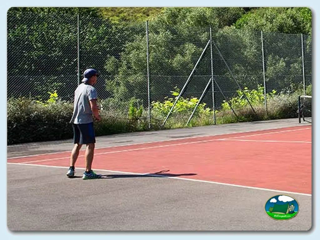 Pista de tenis con jugador del Camping Arenal de Moris, Caravia Alta (Asturias)