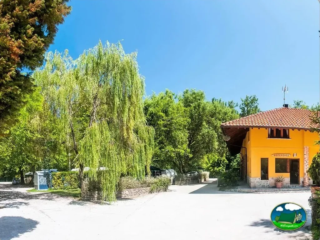 Recepción con arquitectura tradicional y entorno arbolado del Camping Playa de Vega, La Vega (Asturias)