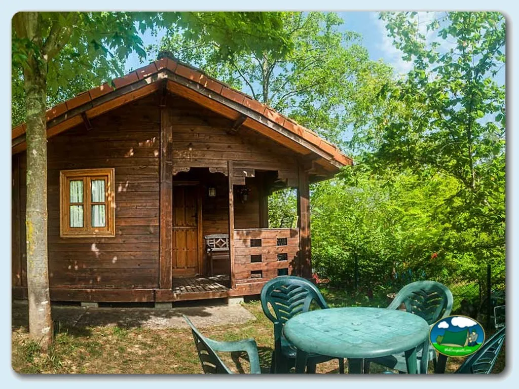 Cabaña de madera con porche y parcela arbolada del Camping Playa de Vega, La Vega (Asturias)
