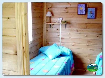 Cabaña interior con cama y paredes de madera del Camping Ribadesella, Ribadesella (Asturias)