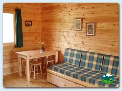 Cabaña interior con sofá y mesa de comedor del Camping Ribadesella, Ribadesella (Asturias)