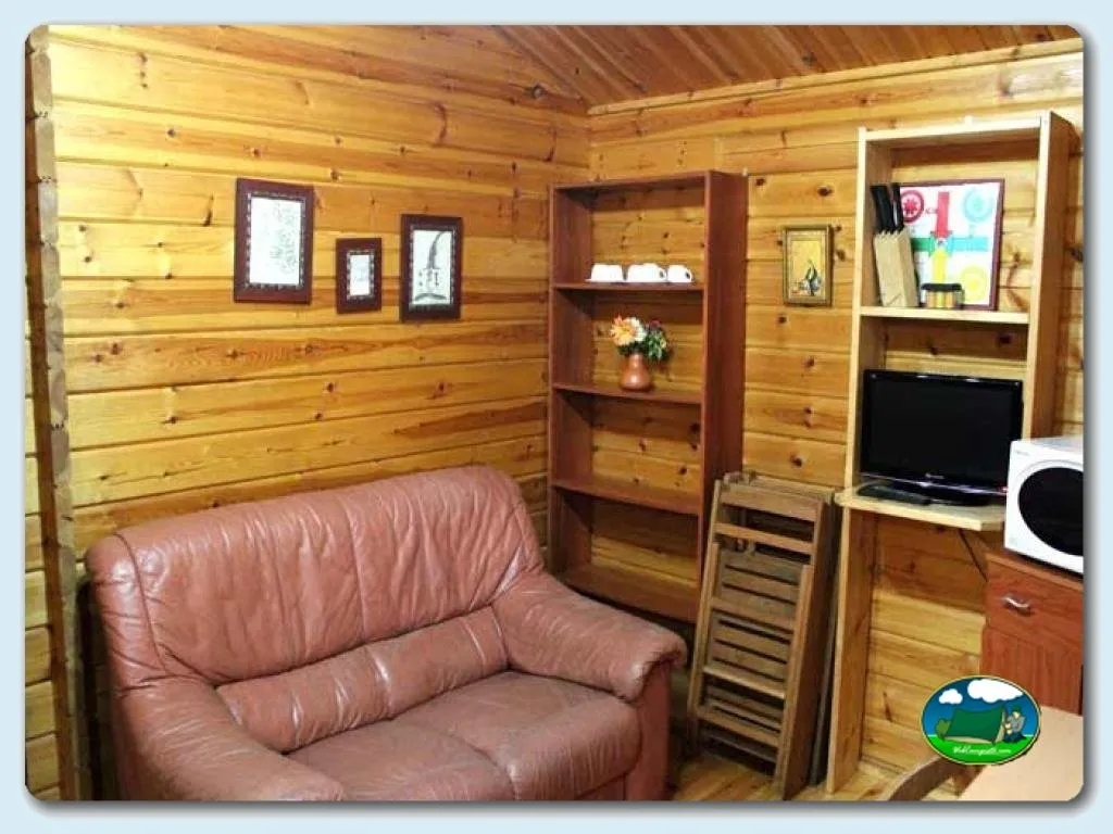 Cabaña interior con sillón, muebles de madera y televisión del Camping Ribadesella, Ribadesella (Asturias)