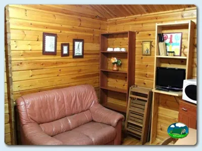 Cabaña interior con sillón, muebles de madera y televisión del Camping Ribadesella, Ribadesella (Asturias)