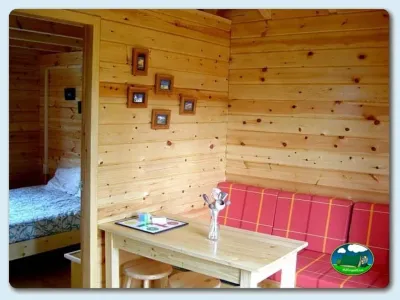 Cabaña de madera interior con zona de estar y dormitorio del Camping Ribadesella, Ribadesella (Asturias)