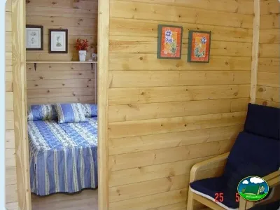 Cabaña de madera con dormitorio y zona de estar del Camping Ribadesella, Ribadesella (Asturias)