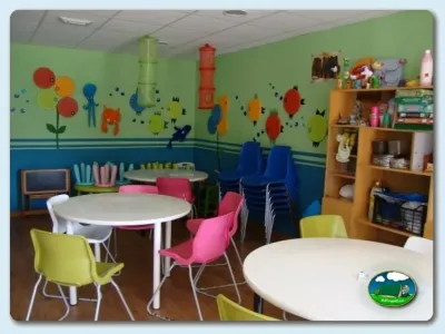 Parque infantil interior con mesas redondas y sillas de colores del Camping Ribadesella, Ribadesella (Asturias)