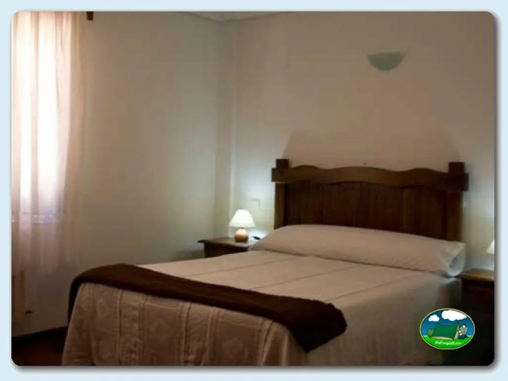 Habitación con cama de madera y mesilla del Camping La Viorna, Mieses (Cantabria)