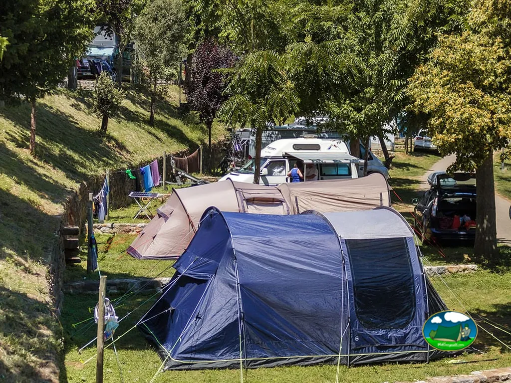 Parcela con tienda de acampada y mobil-home bajo arboleda del Camping La Viorna, Mieses (Cantabria)