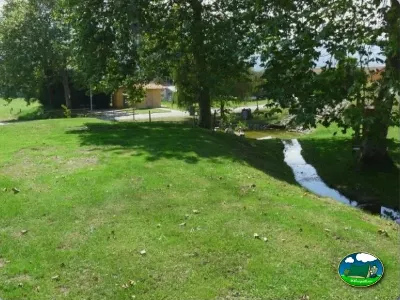 Parcela junto al río con árboles frondosos del Camping Colombres, Colombres en Ribadedeva (Asturias)