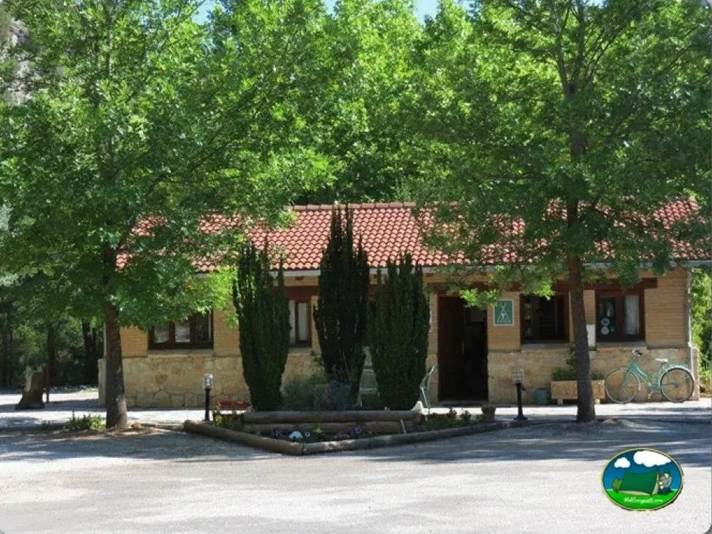 Recepción con arquitectura mediterránea y árboles del Camping Cañón del Río Lobos, Ucero (Soria)