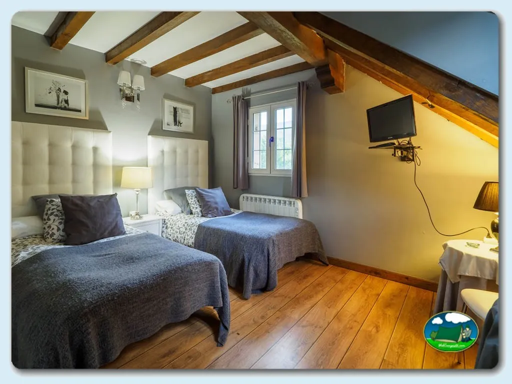 Bungalow interior con dos camas y vigas de madera del Camping Puente Romano, Riaño (Cantabria)