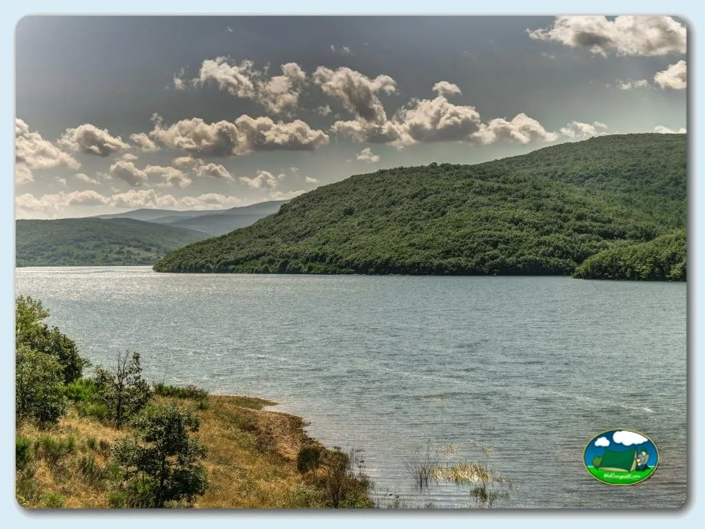 Lago rodeado de montaña boscosa del Camping Puerta de la Demanda, Villasur de Herreros (Burgos)