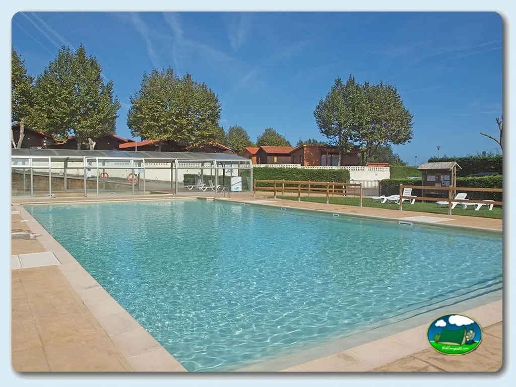 Piscina con vistas a bungalows y árboles del Camping Oyambre, san Vicente de la Barquera (Cantabria)
