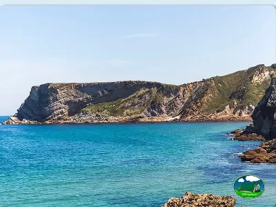 Playa junto al mar con acantilados y agua turquesa del Camping Comillas, Comillas (Cantabria)