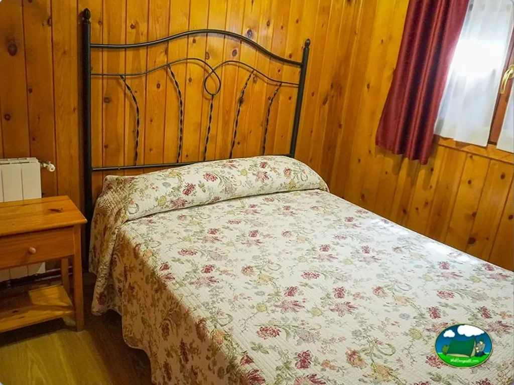 Cabaña interior con cama de matrimonio y paredes de madera del Camping Costa San Juan de la Canal, Soto de la Marina (Cantabria)
