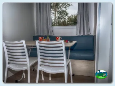 Mobil-home interior con zona de comedor y vistas al bosque del Camping Somo Parque, Ribamontán al Mar (Cantabria)