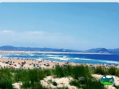 Playa junto al mar con dunas y montañas al fondo del Camping Derby de Loredo, Loredo (Cantabria)