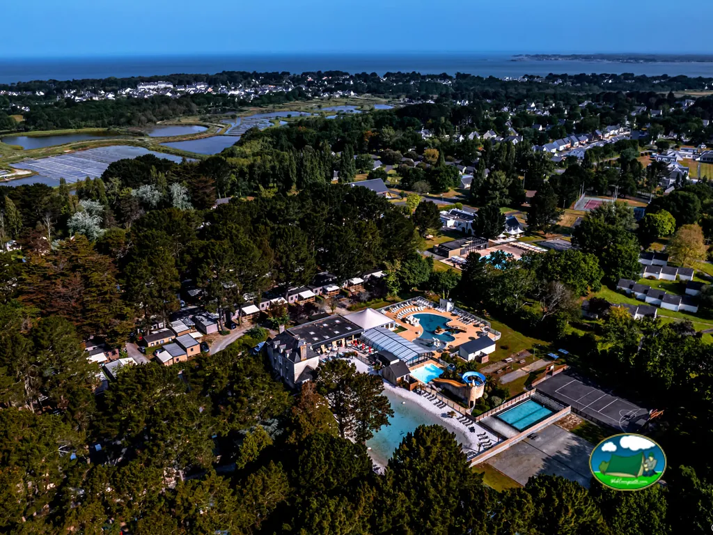 vista aérea al atardecer del camping con piscinas, tobogán y el mar al fondo en Mesquer
