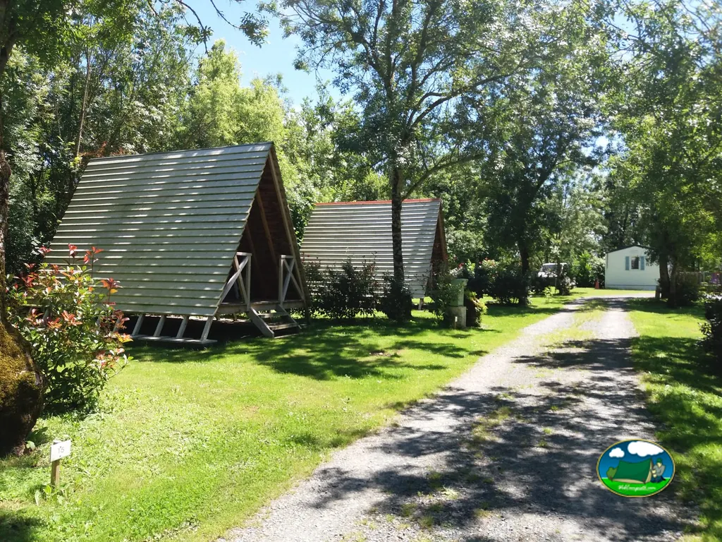cabañas de madera tipo A-frame entre árboles junto a un camino de grava en Le Langon