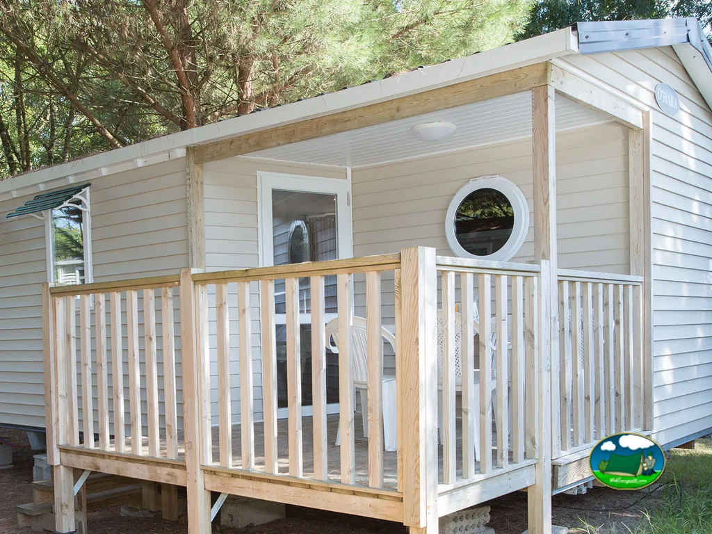 terraza de madera con mesa y sillas en un mobil-home entre pinos en La Tremblade