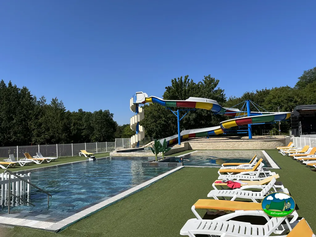 piscina con tobogán multicolor y tumbonas vacías bajo cielo despejado en Saint-Mandé-sur-Brédoire