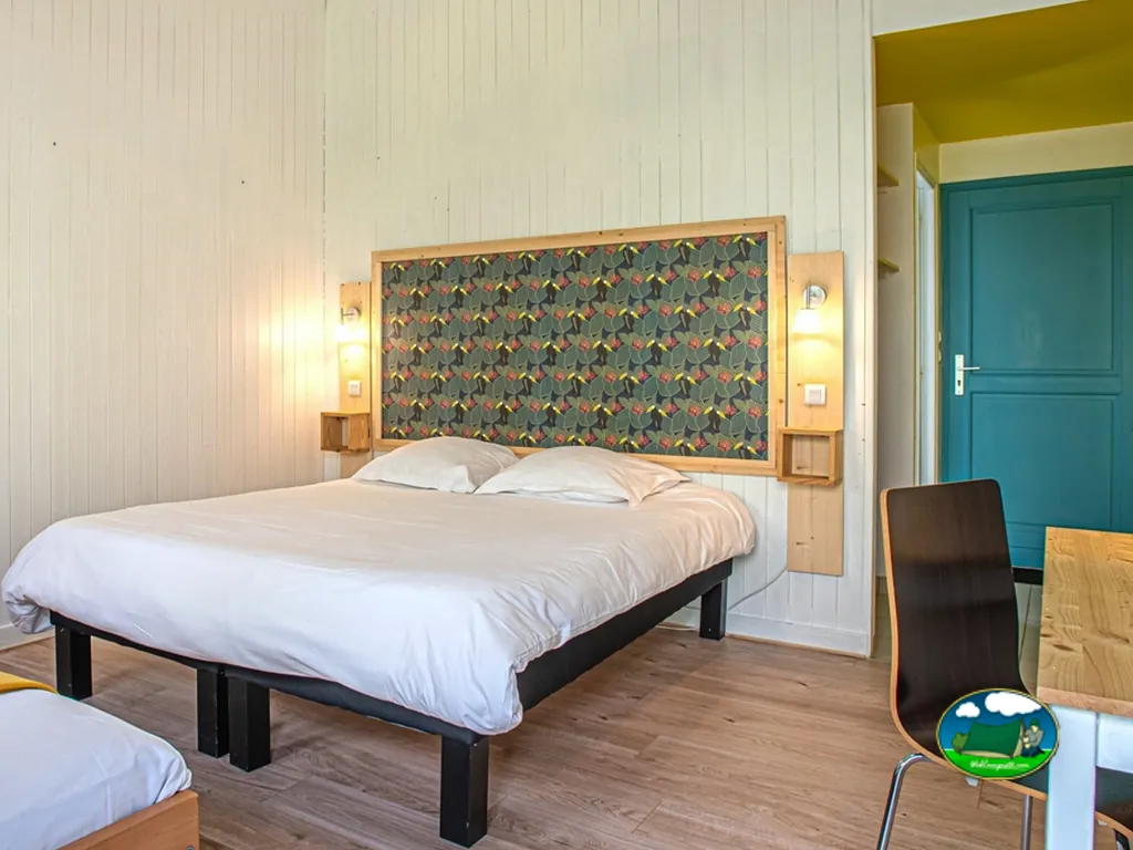 dormitorio de un mobil-home con cama de matrimonio y puerta turquesa en Plouhinec