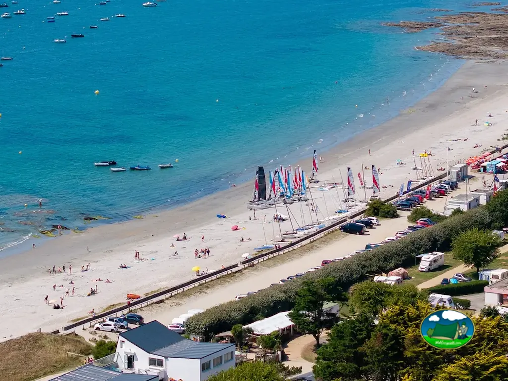 vista aérea de una playa concurrida con veleros varados y el camping entre árboles junto al mar en Sarzeau