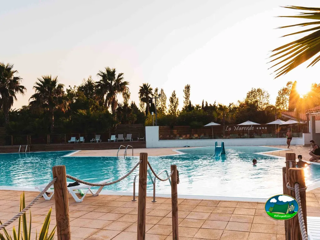 piscina del camping La Marende al atardecer con tobogán, sombrillas y bañistas