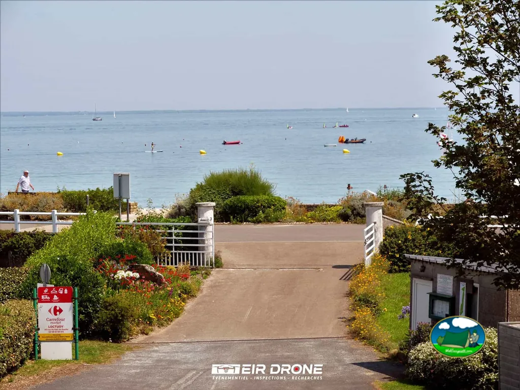 entrada del camping con acceso directo a la playa y embarcaciones en el mar al fondo