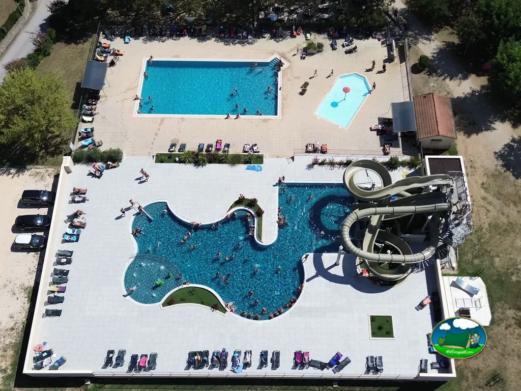 vista aérea de piscina con tobogán, bañistas y tumbonas junto al aparcamiento en Rosières