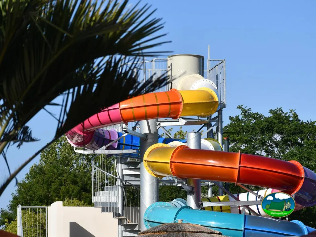 torre de toboganes acuáticos multicolor junto a una palmera en Château-d'Olonne