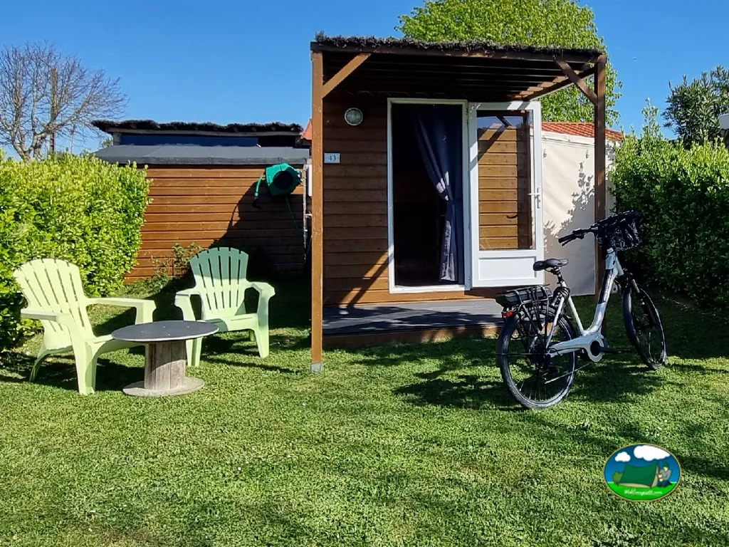 cabaña de madera con terraza, sillas y bicicletas en el jardín en Talmont-Saint-Hilaire