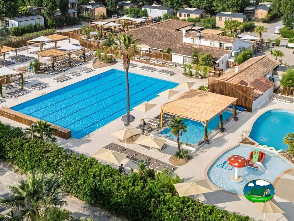 vista aérea de piscinas con tumbonas, sombrillas y toboganes infantiles del camping en Fréjus