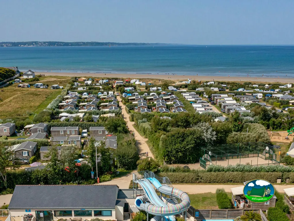 vista aérea del camping con mobil-homes, tobogán acuático y pista deportiva junto a la playa en Plonévez-Porzay