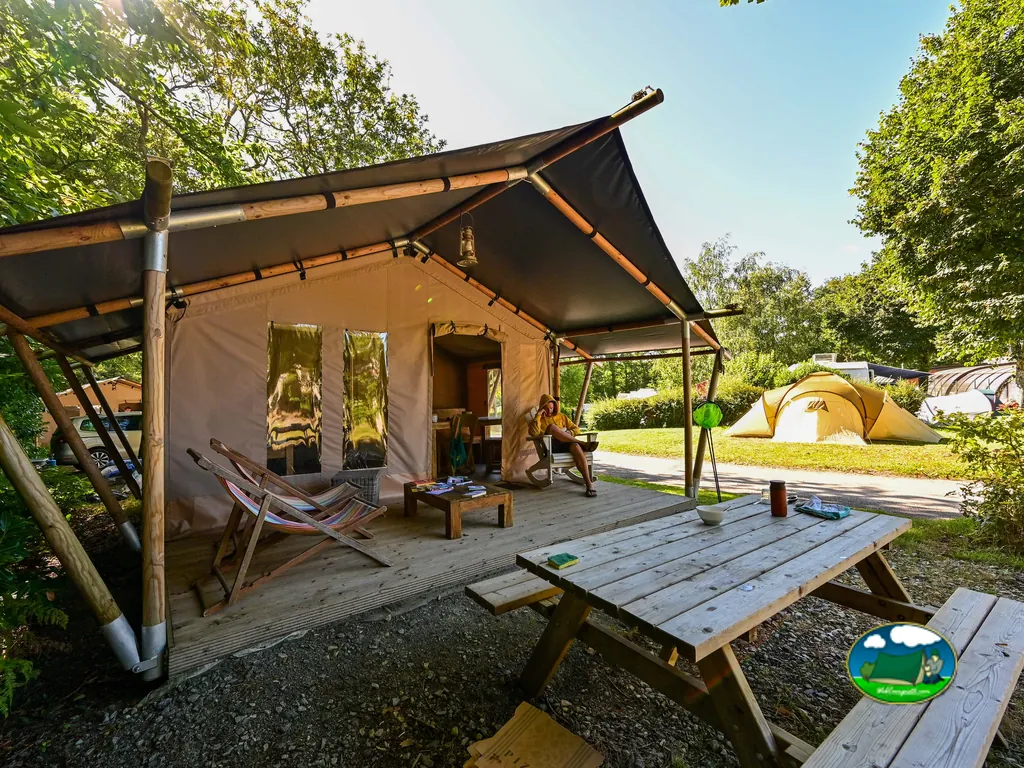 tienda glamping con porche y mesa de pícnic junto a otras tiendas de campaña