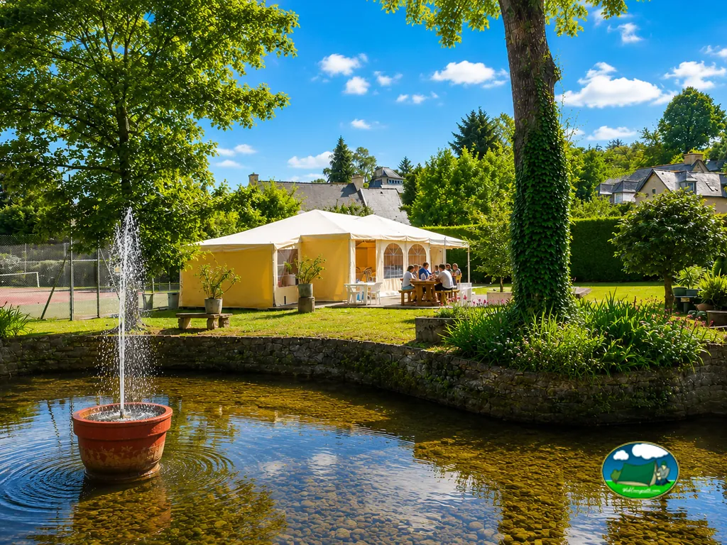estanque con fuente y carpa blanca junto a una pista de tenis en el jardín del camping