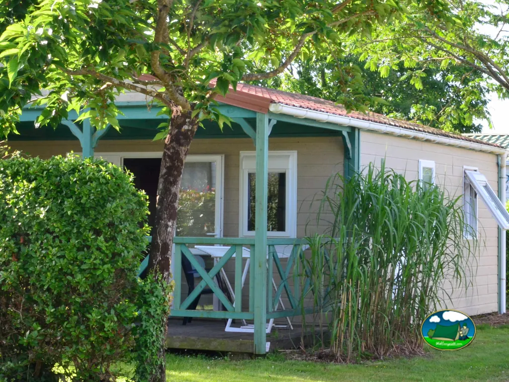 bungaló con porche y tejado a dos aguas entre vegetación en el camping Les Logeries en Vairé