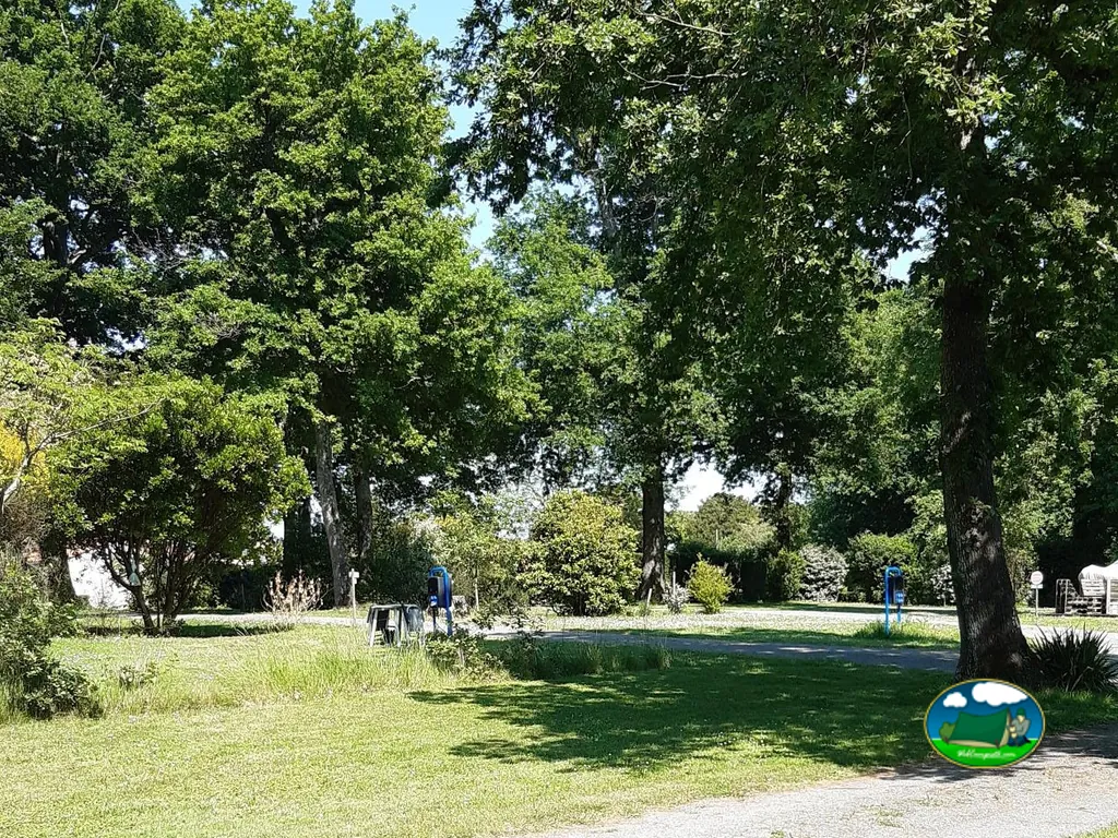 parcelas arboladas con toma eléctrica y camino de gravilla del camping du Parc en Étaules