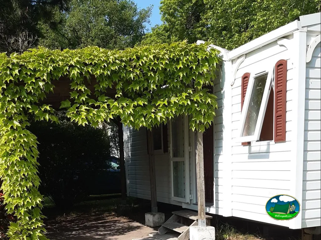 bungaló blanco con porche cubierto de hiedra en el camping du Parc en Étaules