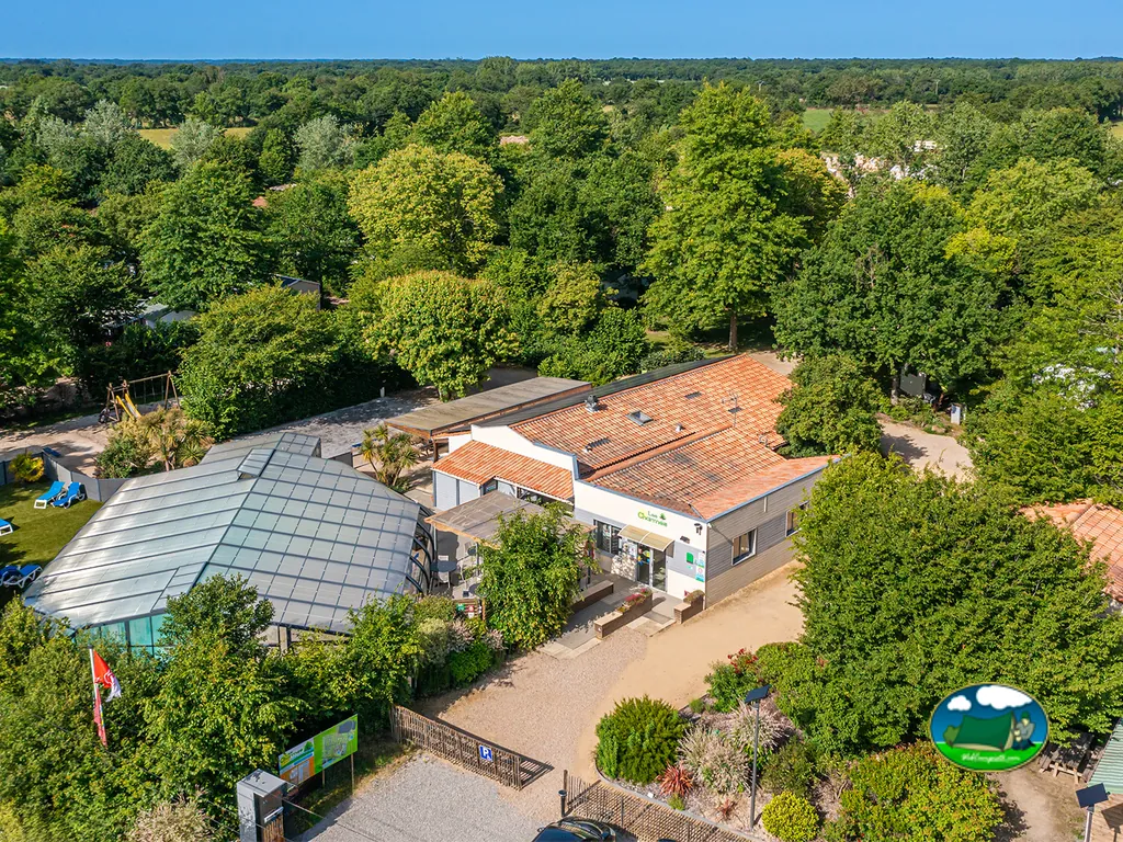 vista aérea de la recepción acristalada y el edificio principal rodeados de árboles en Apremont