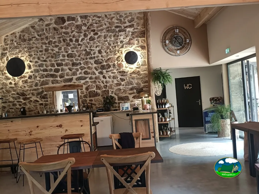 interior del bar con pared de piedra vista, mesas de madera y reloj decorativo