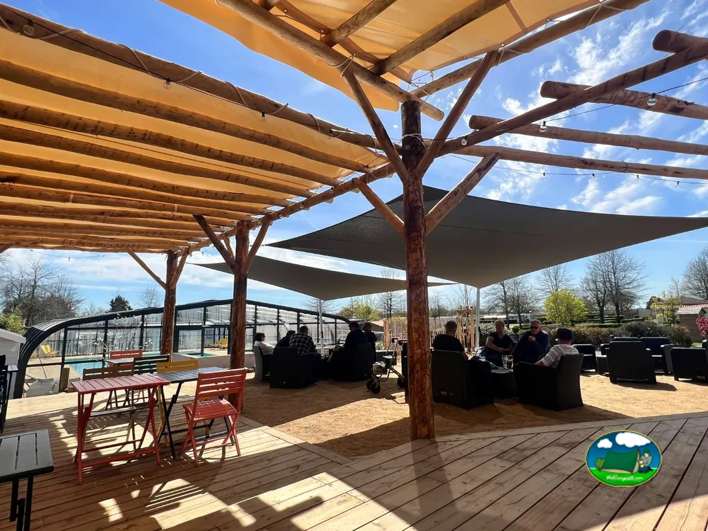 terraza cubierta por pérgolas de madera con clientes sentados junto a la piscina cubierta