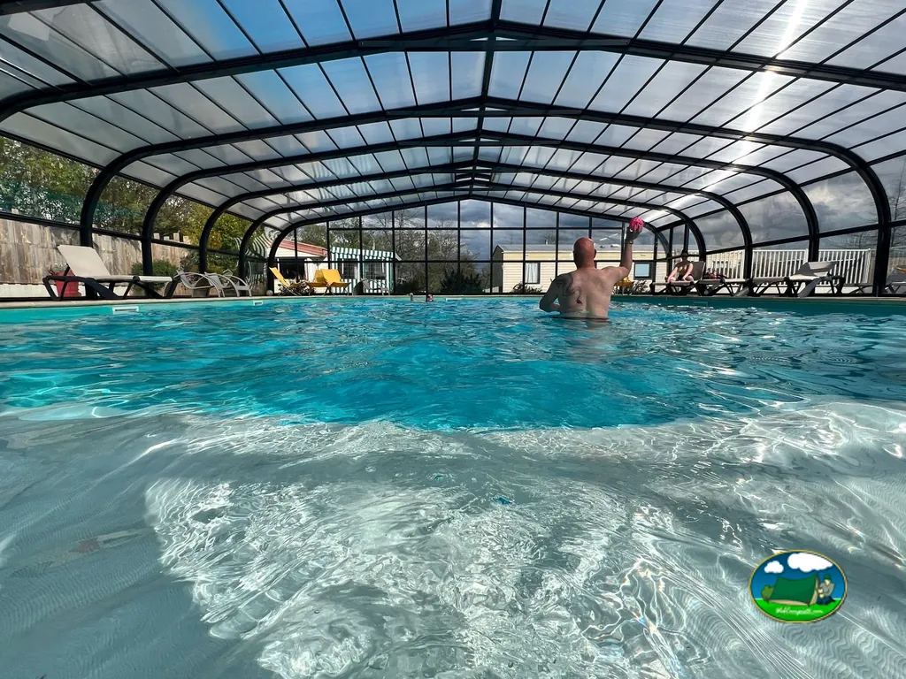 hombre bañándose de espaldas en la piscina cubierta con otra persona al fondo