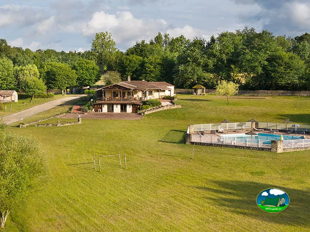 vista aérea de la casa señorial de piedra con jardín, piscina y portería de fútbol en Saint-Géraud-de-Corps
