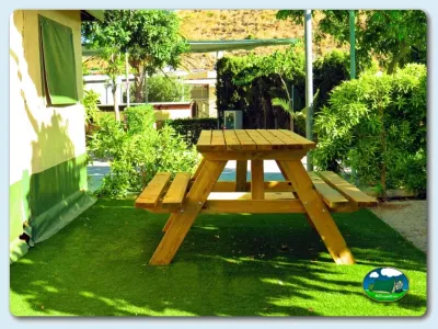 Parcela con mesa de madera y zona ajardinada del Camping Los Escullos, Almería (Almería)