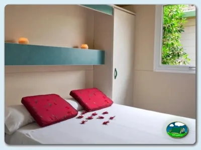 Bungalow habitación con cama doble y almohadas rojas del Camping Los Escullos, Almería (Almería)