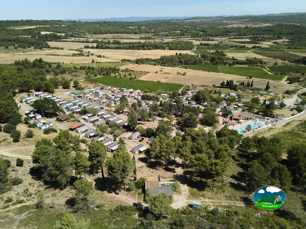vista aérea del camping con mobile homes, piscina y viñedos alrededor en Villeveyrac