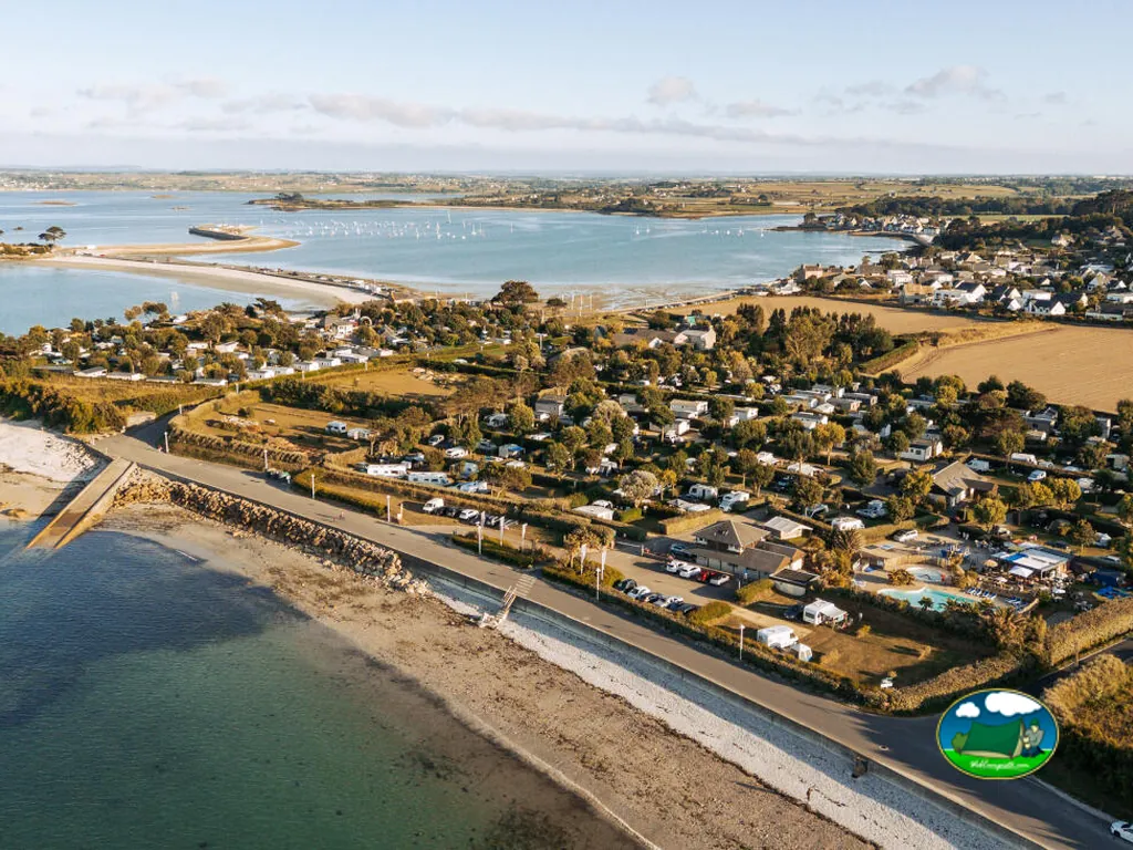 vista aérea del camping junto a la playa con piscina y parcelas arboladas en Saint-Pol-de-Léon
